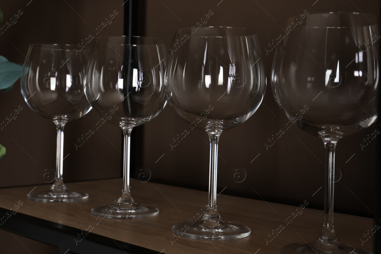 Photo of Empty wine glasses on shelf near brown wall