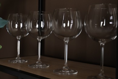 Photo of Empty wine glasses on shelf near brown wall