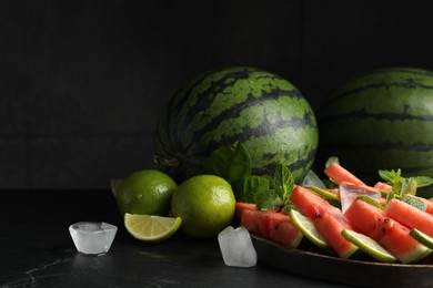 Photo of Tasty sliced watermelon, limes, mint and ice on black table