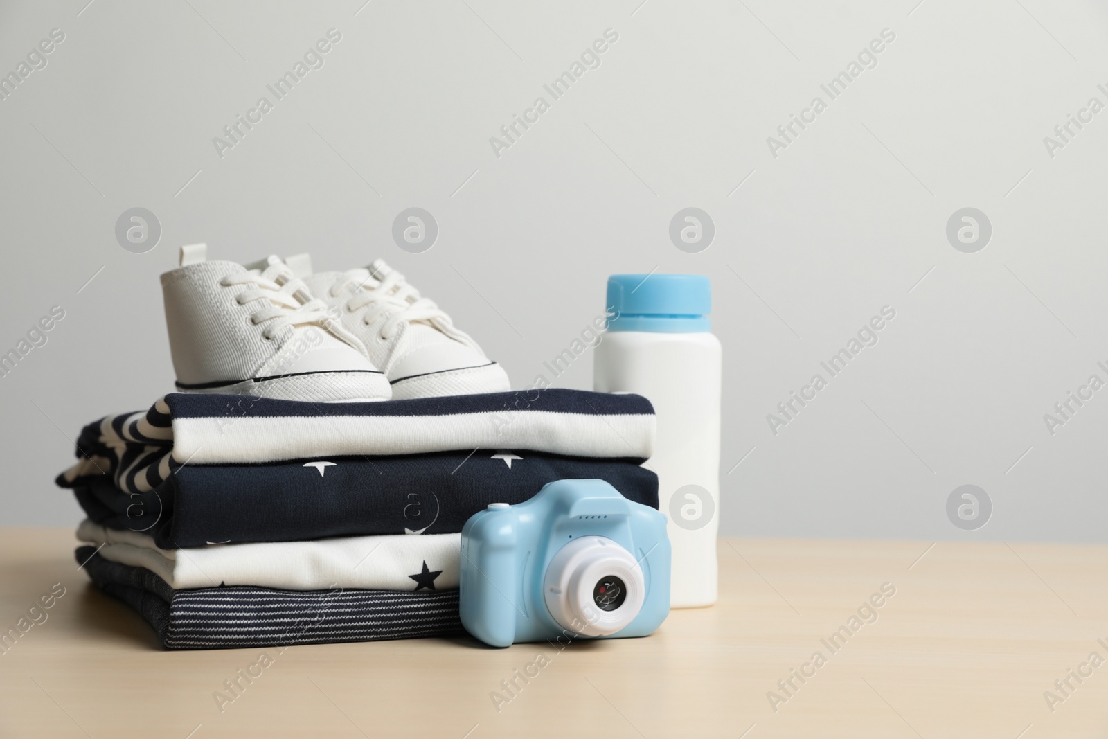 Photo of Baby clothes, shoes and toy camera on wooden table. Space for text