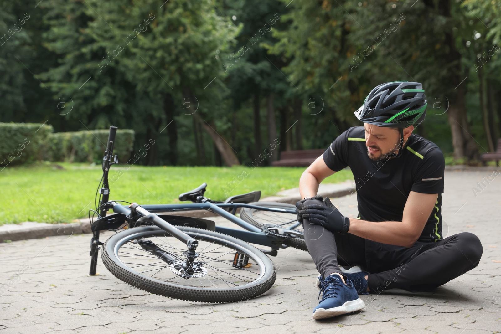 Photo of Man with injured knee near bicycle outdoors