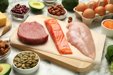 Photo of Different fresh products on white marble table. Sources of essential amino acids