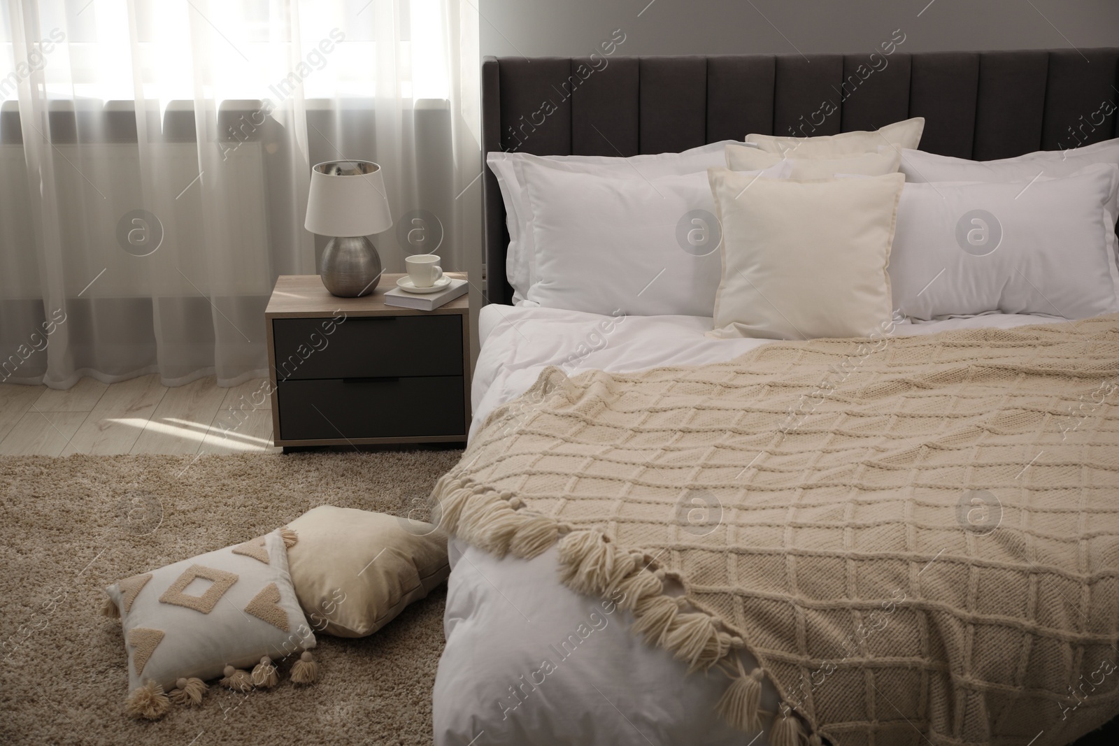 Photo of Many soft white pillows and knitted blanket on bed indoors