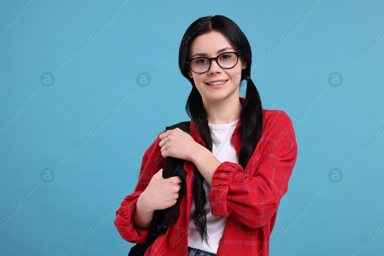 Photo of Smiling student in glasses with backpack on light blue background