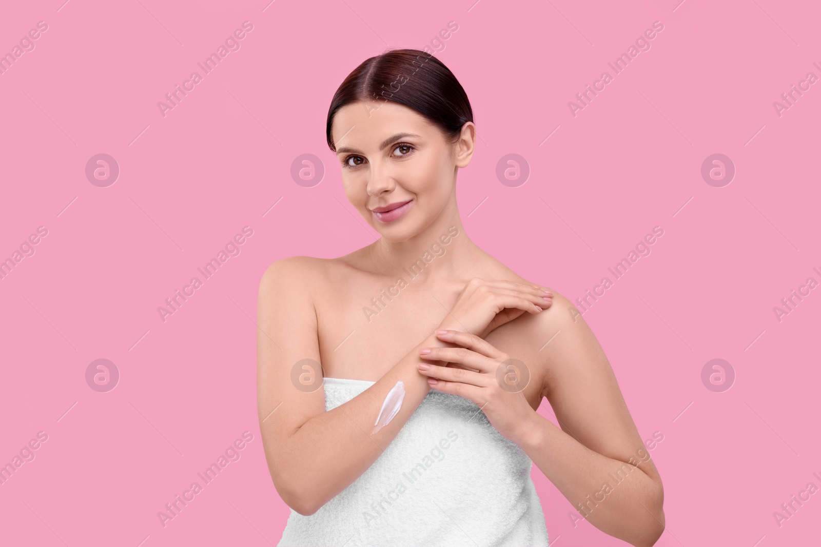 Photo of Beautiful woman with smear of body cream on her arm against pink background