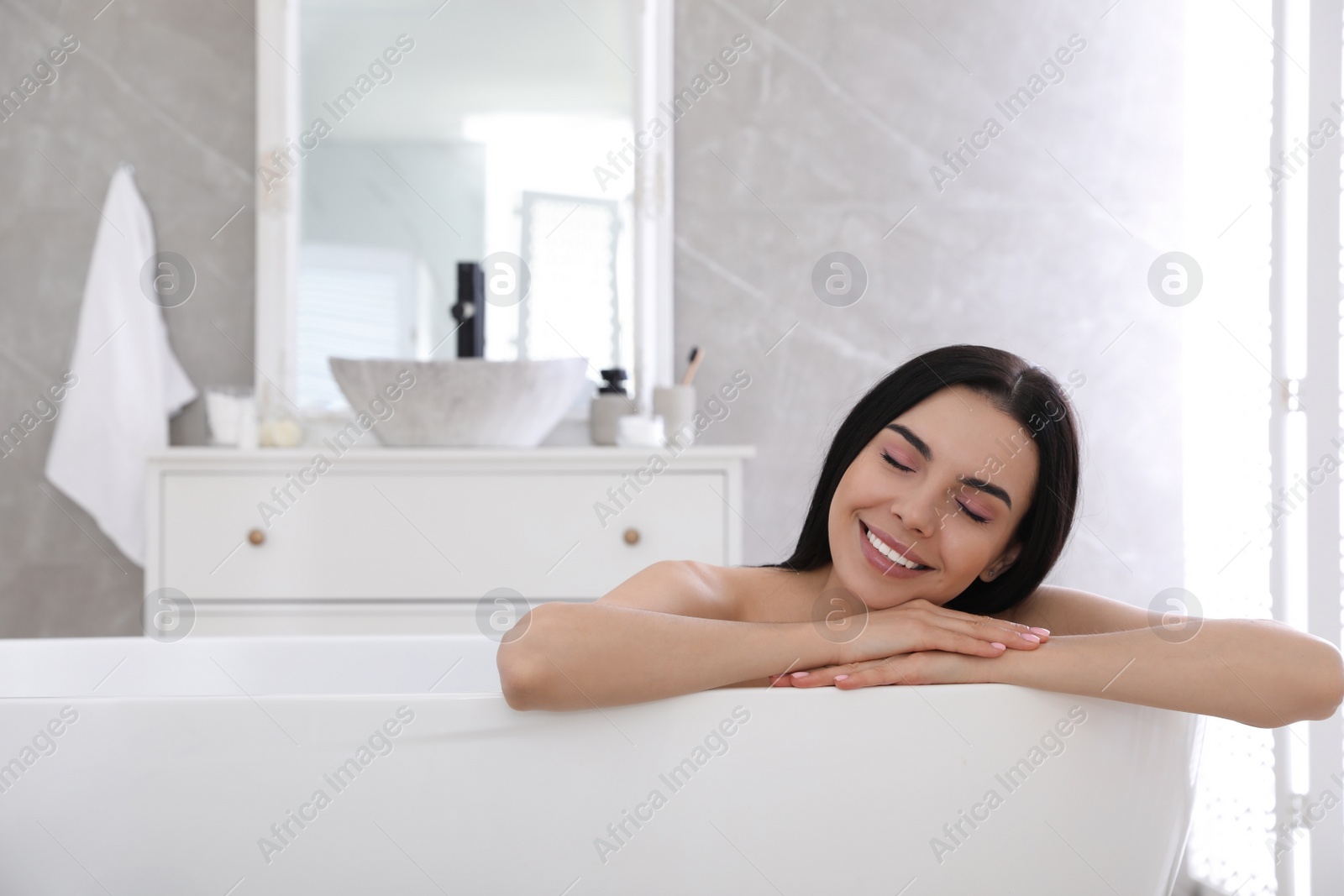 Photo of Beautiful young woman relaxing in bathtub at home