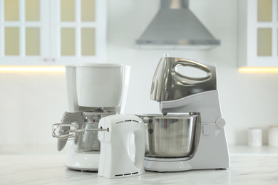 Photo of Set of modern home appliances on white marble table in kitchen