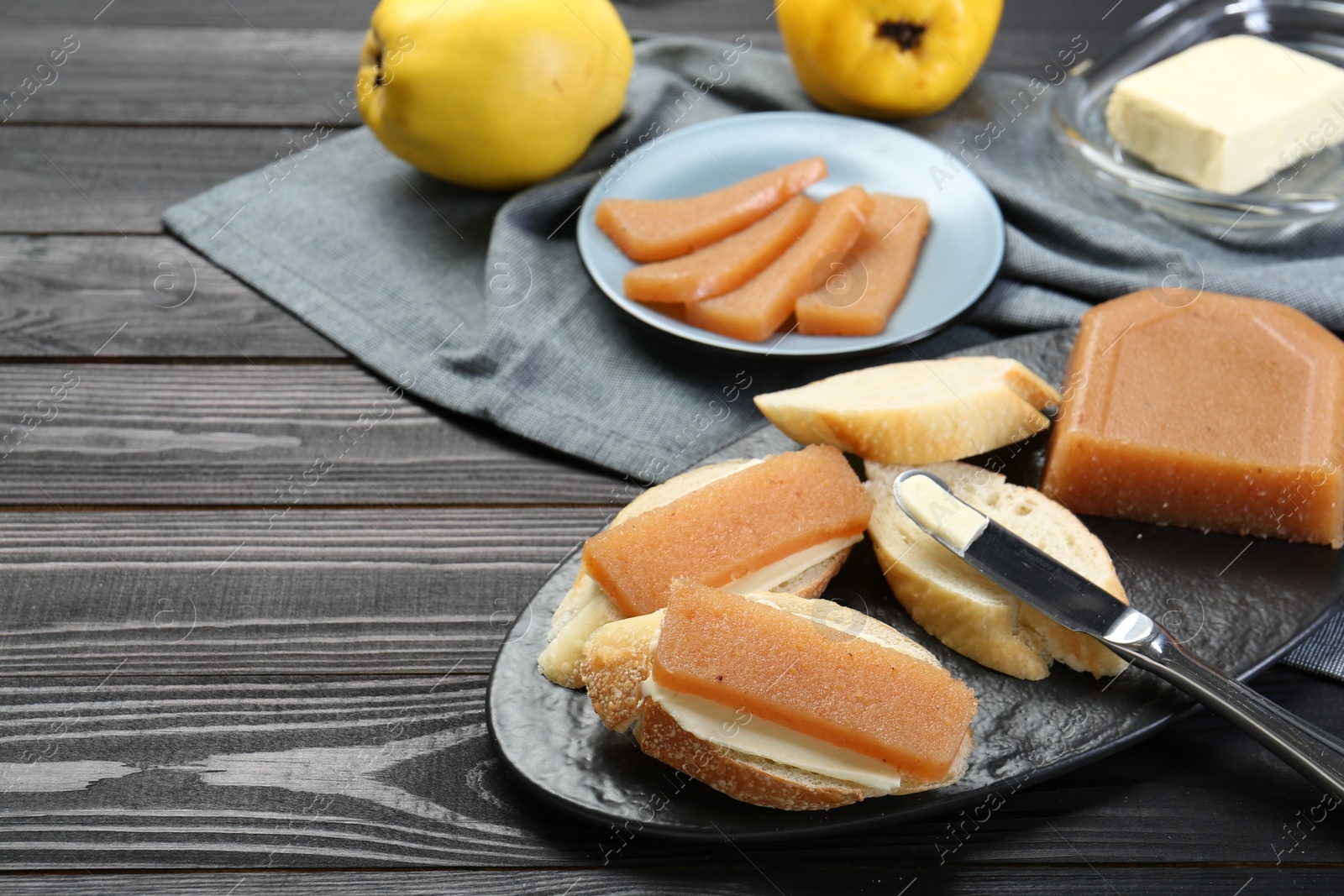 Photo of Tasty sandwiches with quince paste served on black wooden table, space for text