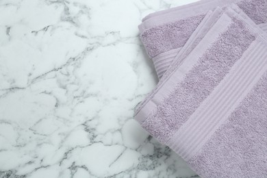 Photo of Violet terry towels on white marble table, top view. Space for text