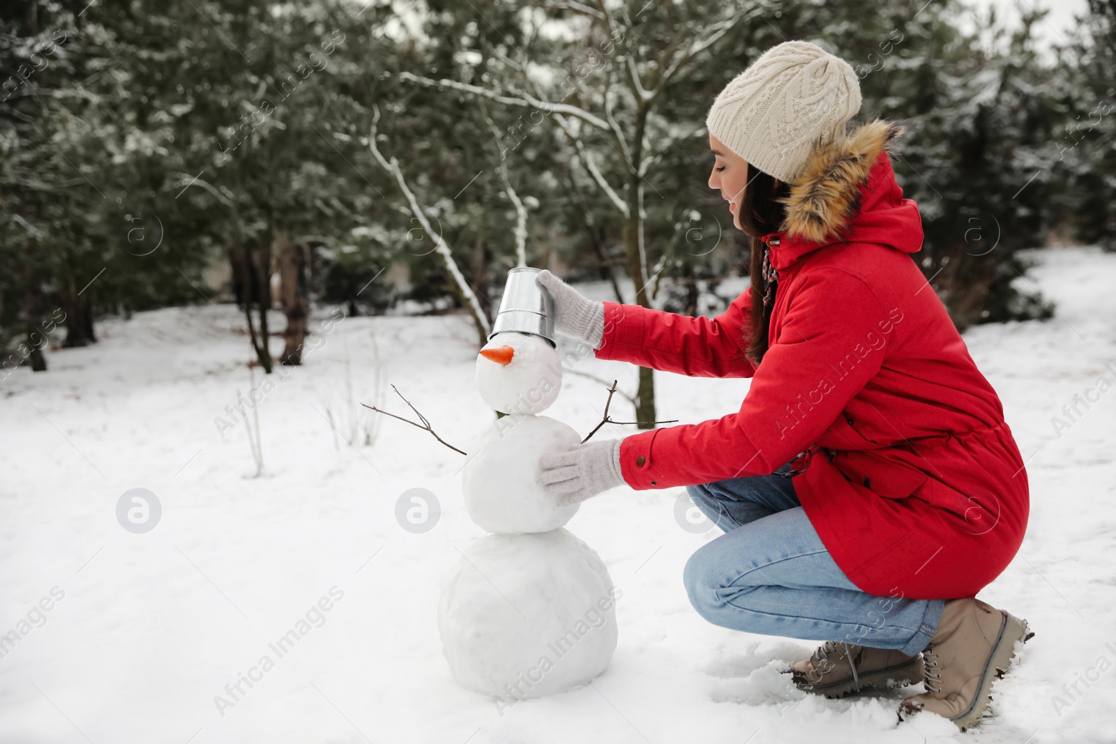 Photo of Young woman making snowman outdoors on winter day. Space for text