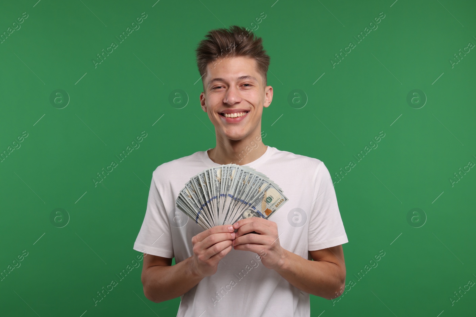 Photo of Happy man with dollar banknotes on green background