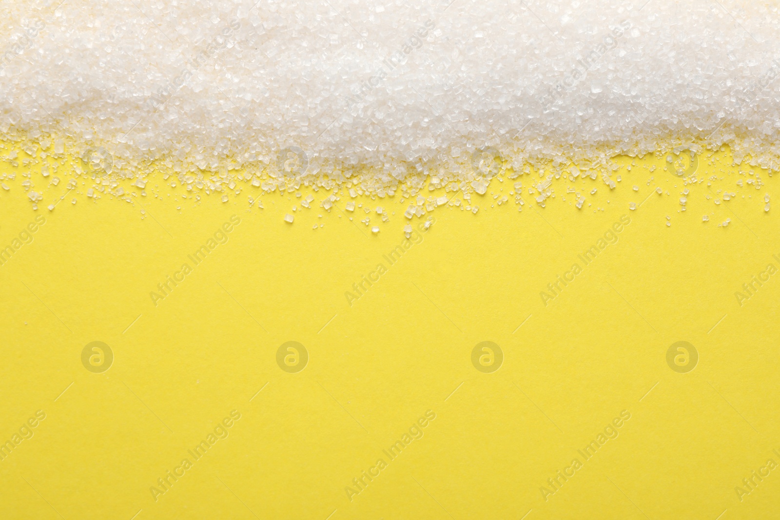 Photo of Granulated sugar on yellow background, top view. Space for text