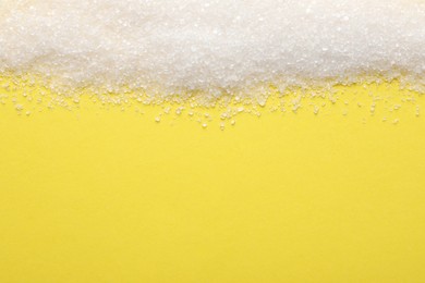 Granulated sugar on yellow background, top view. Space for text