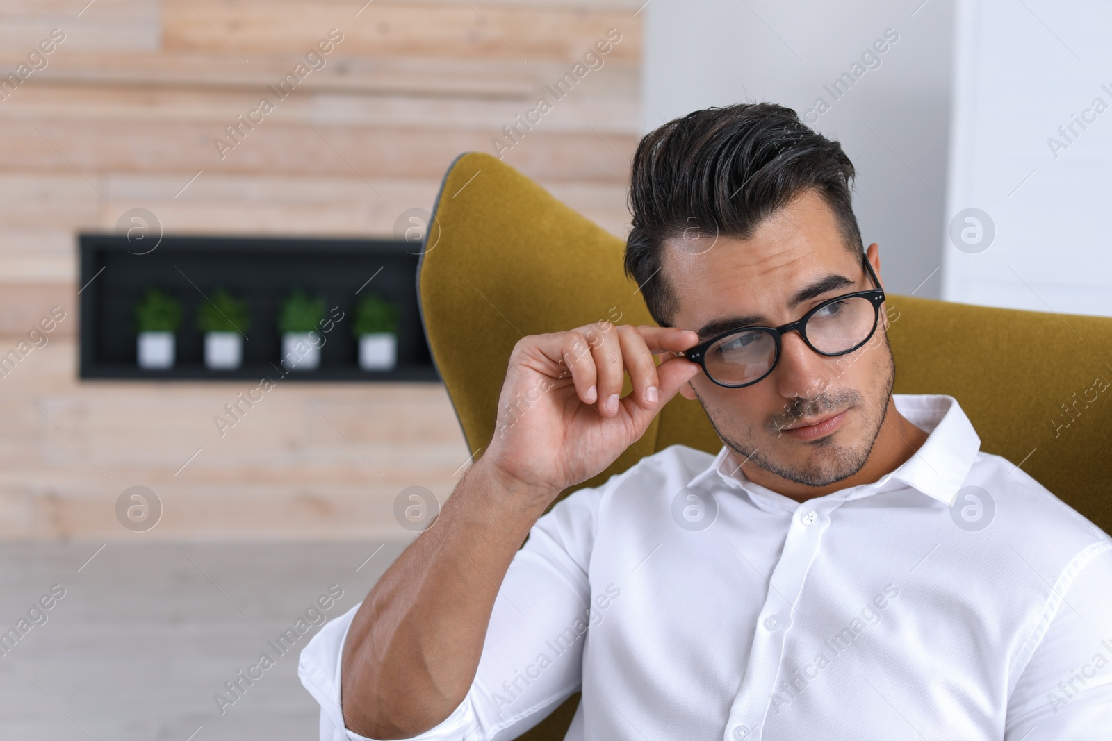 Photo of Portrait of handsome young man sitting in armchair indoors