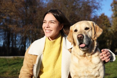 Photo of Beautiful young woman with cute Labrador Retriever on sunny day outdoors