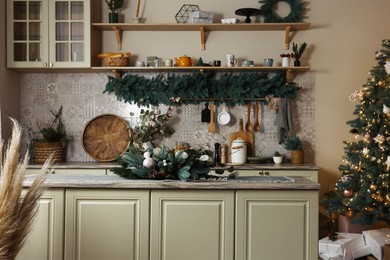 Photo of Stylish kitchen with festive decor and Christmas tree. Interior design