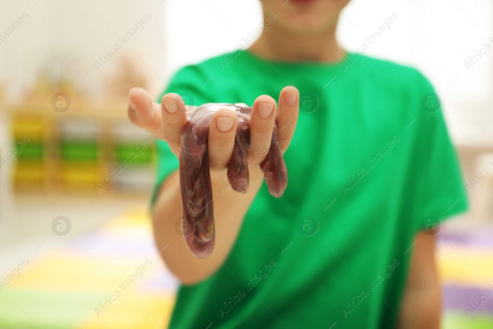 Photo of Little boy holding slime in room, closeup