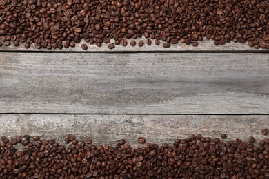 Photo of Roasted coffee beans on wooden table, flat lay. Space for text