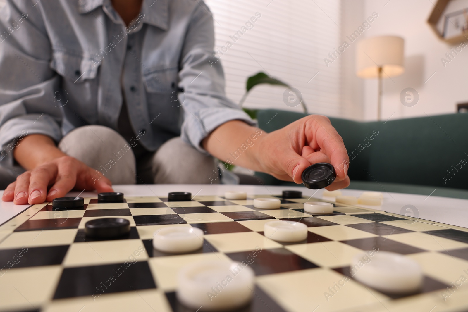 Photo of Woman playing checkers at home, closeup view