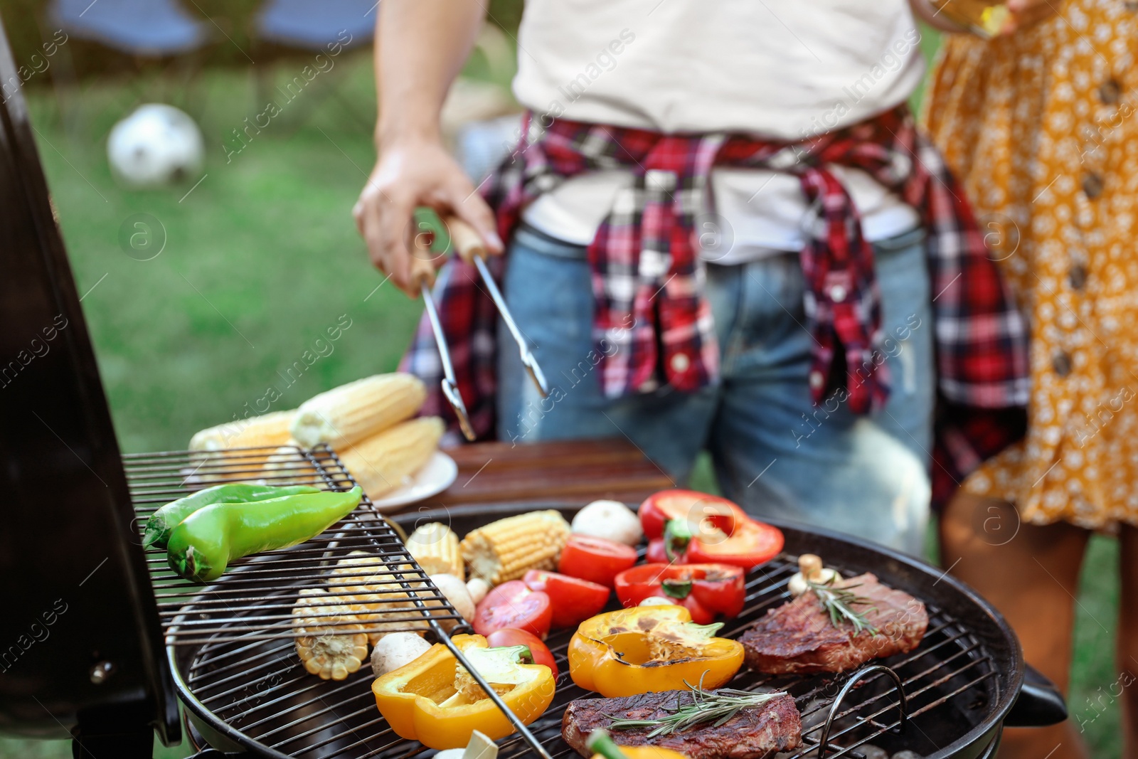 Photo of Man cooking food on barbecue grill outdoors, closeup