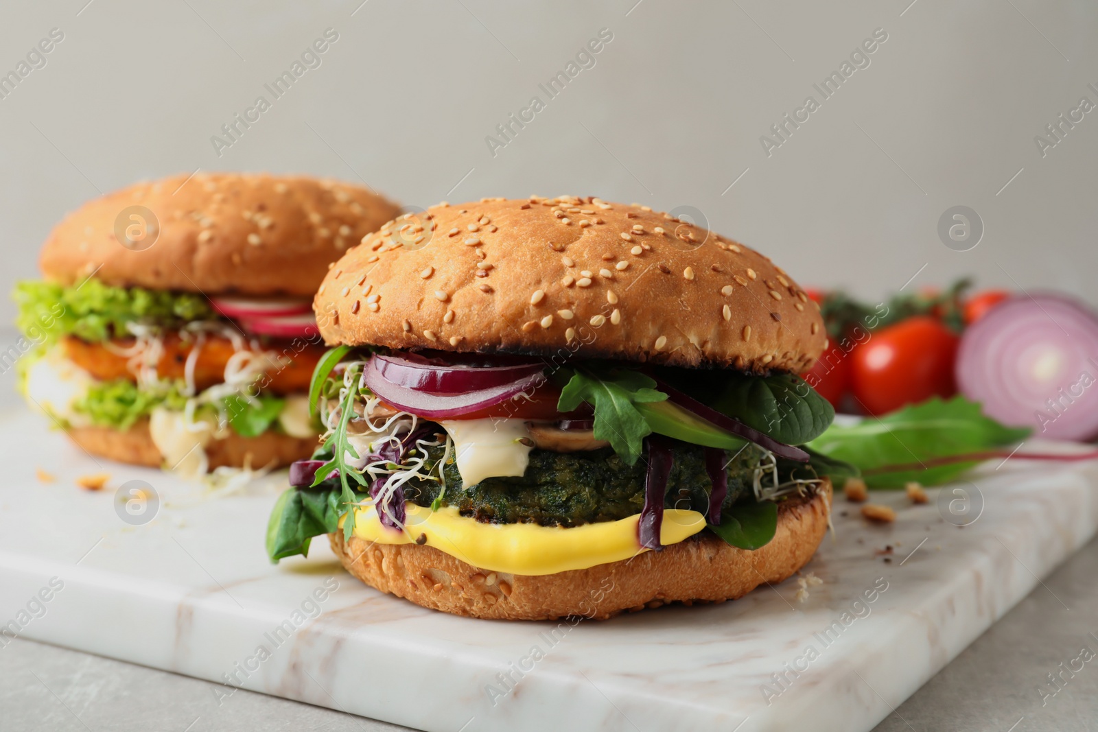 Photo of Board with tasty vegetarian burgers on table