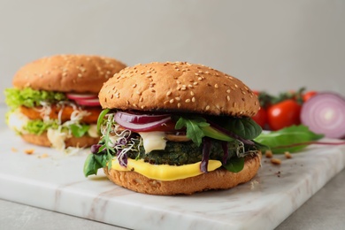 Photo of Board with tasty vegetarian burgers on table