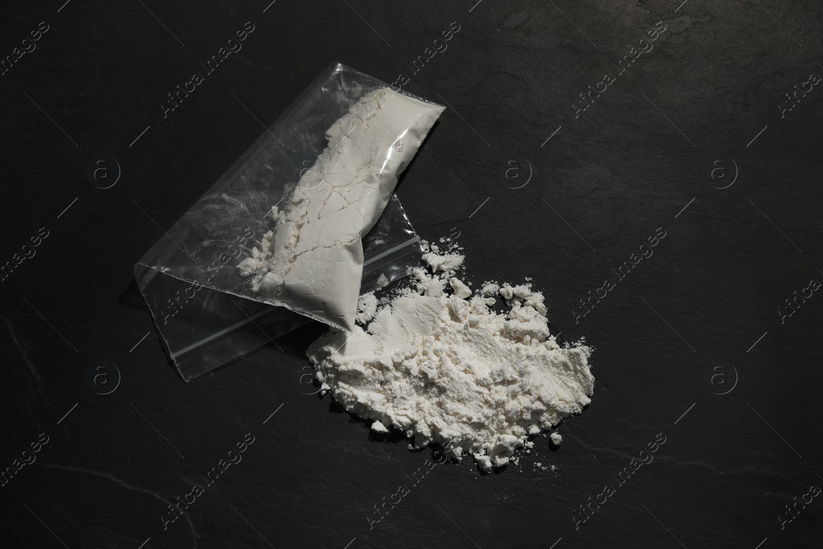 Photo of Drug addiction. Plastic bag with cocaine on dark textured background, closeup