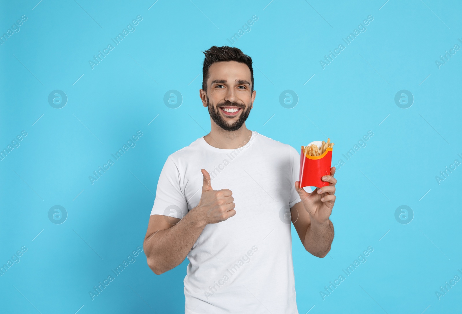 Photo of Man with French fries on light blue background