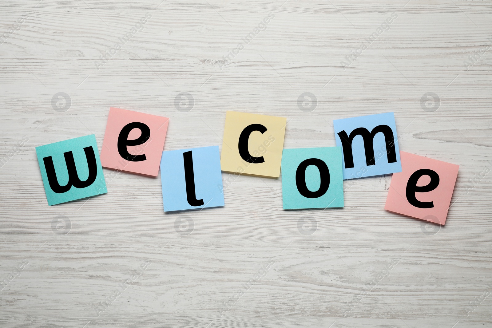 Image of Word Welcome made of paper notes on white wooden table, top view