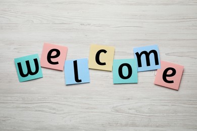 Word Welcome made of paper notes on white wooden table, top view