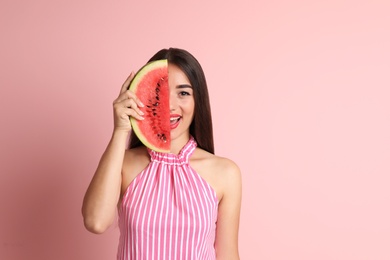 Beautiful young woman posing with watermelon on color background