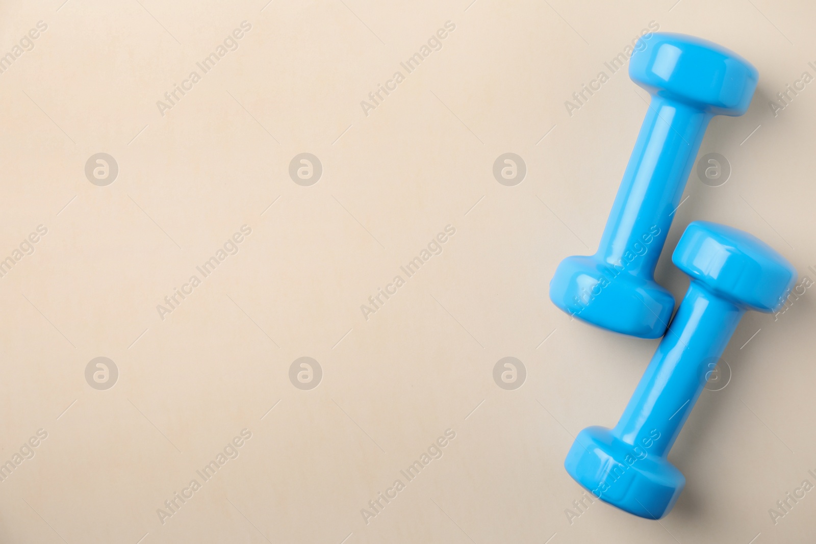 Photo of Bright dumbbells and space for text on color background, flat lay. Home fitness