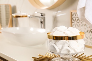 Decorative jar with cotton pads on modern countertop in bathroom interior