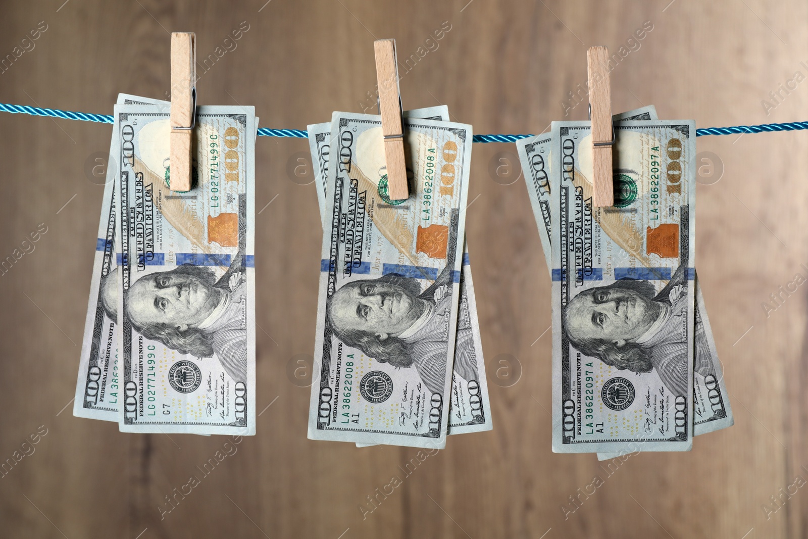 Photo of Dollar banknotes hanging on rope against wooden background