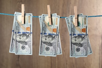 Photo of Dollar banknotes hanging on rope against wooden background