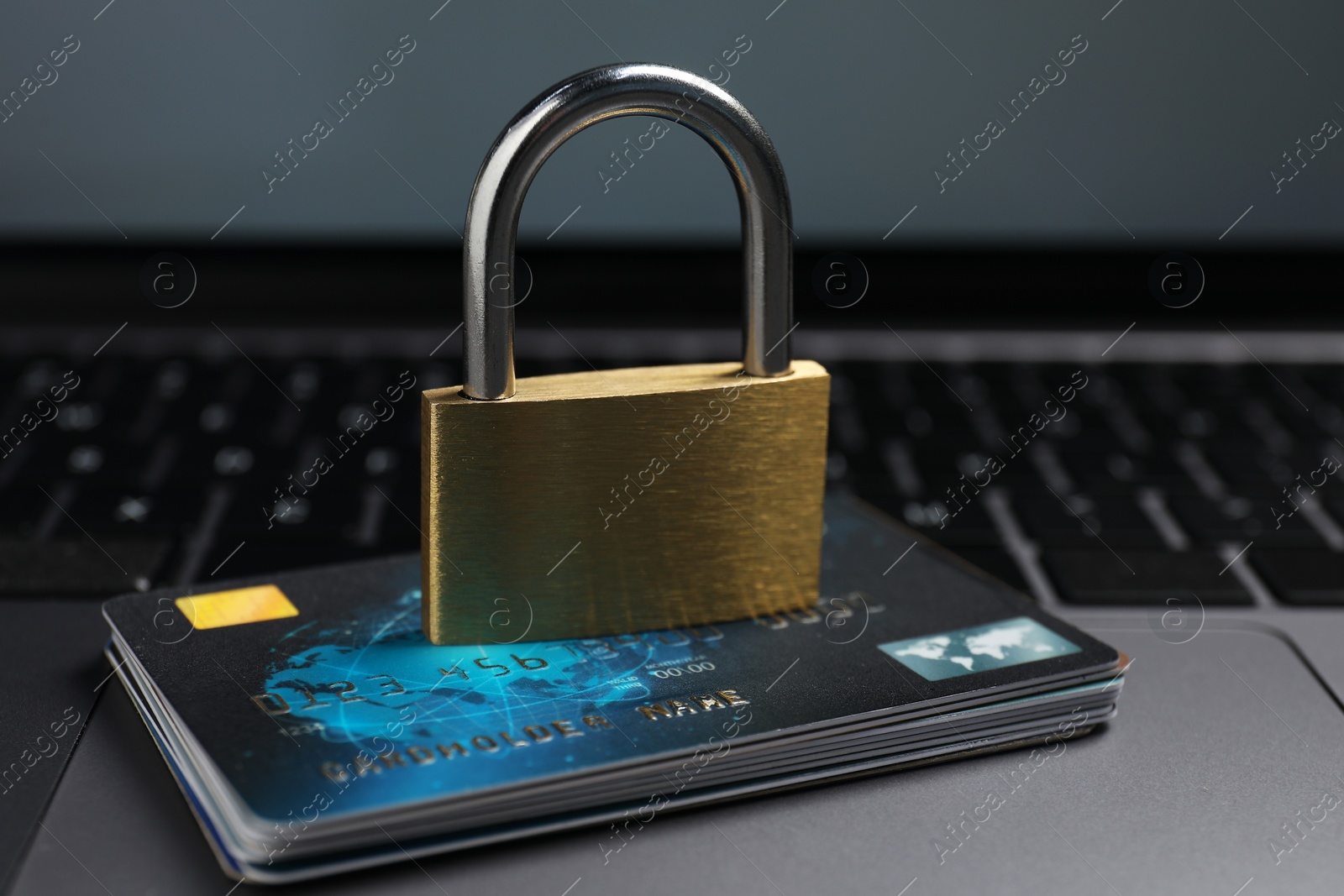 Photo of Cyber security. Metal padlock and credit cards on laptop, closeup