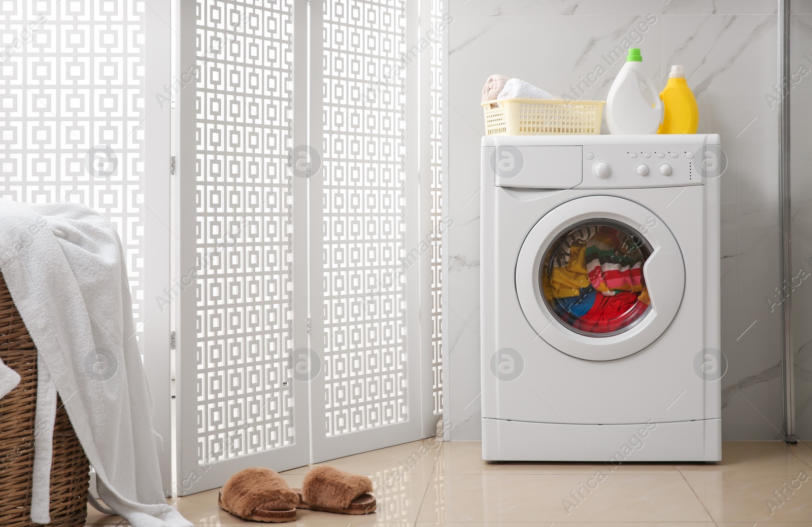 Photo of Modern washing machine with clothes in bathroom