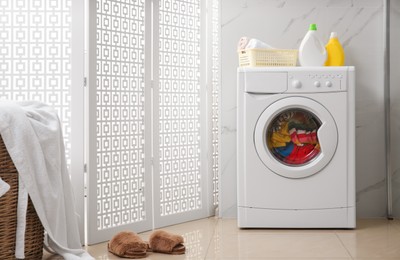 Photo of Modern washing machine with clothes in bathroom