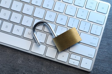 Cyber security. Open padlock and keyboard on dark grey table, top view