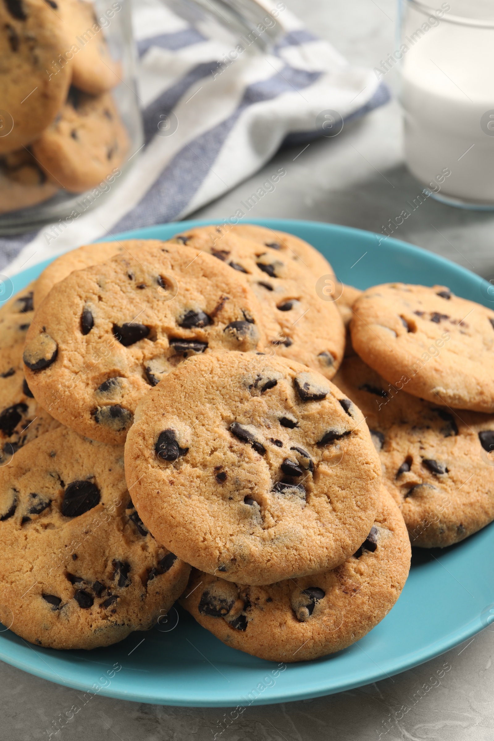 Photo of Plate with delicious chocolate chip cookies on grey marble table, closeup