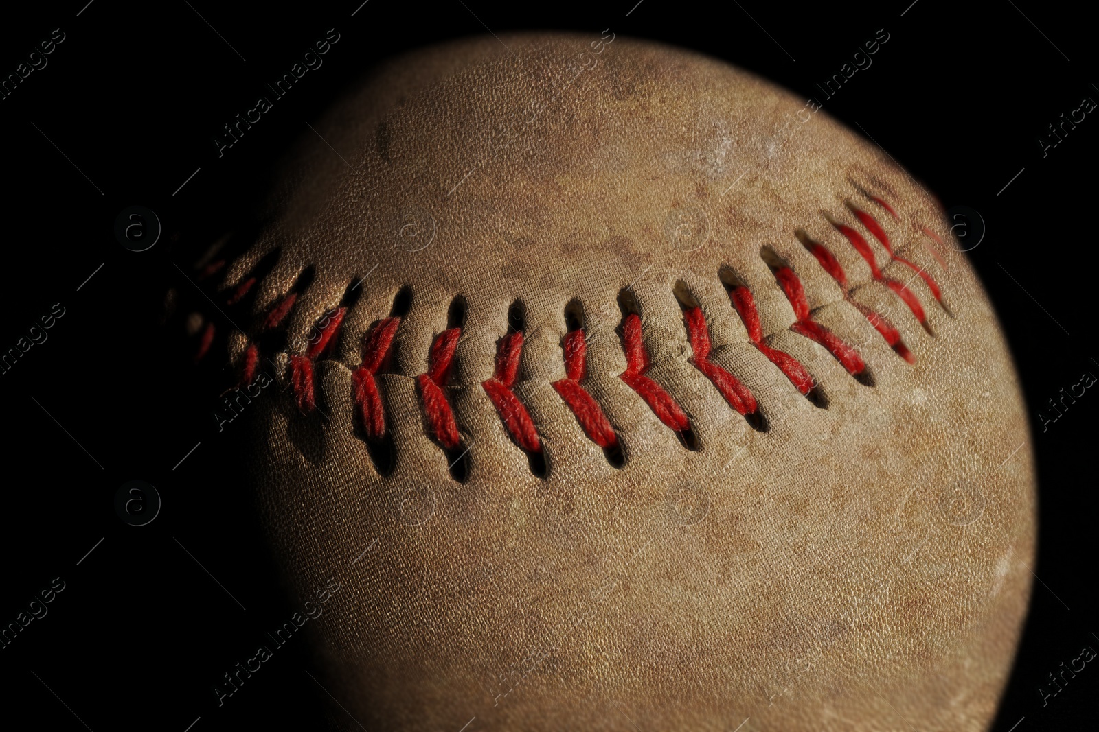 Image of Worn baseball ball on black background, closeup