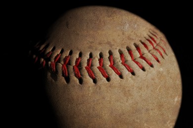 Worn baseball ball on black background, closeup