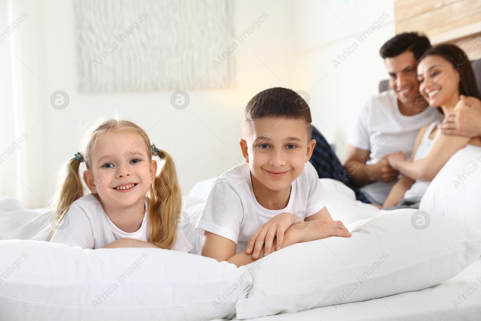 Photo of Cute happy children and their parents on large bed