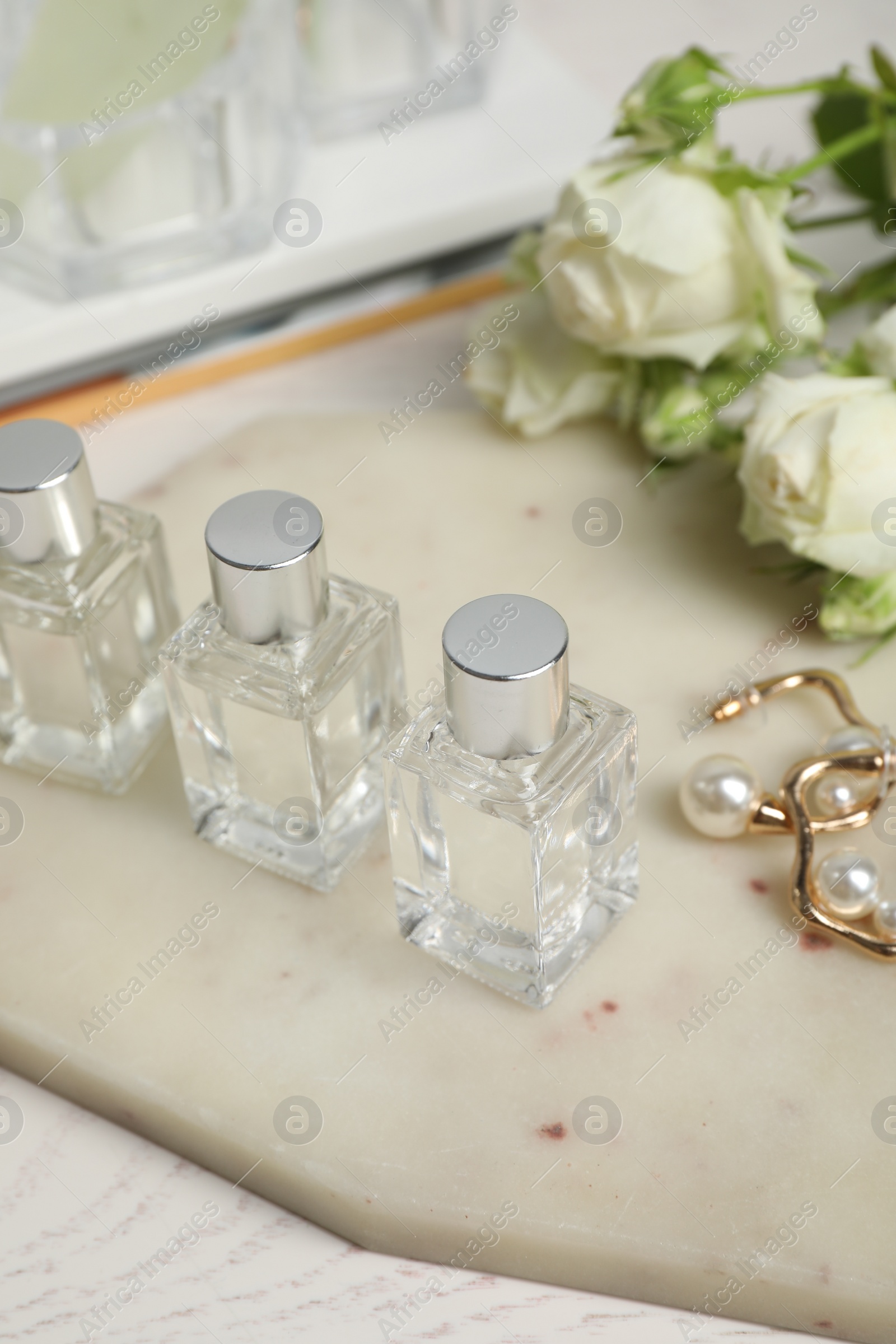 Photo of Perfumes and stylish earrings on white table