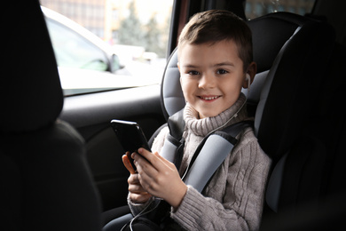 Photo of Cute little boy listening to audiobook in car