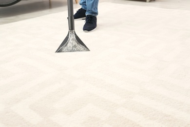 Photo of Man removing dirt from carpet with vacuum cleaner indoors, closeup. Space for text