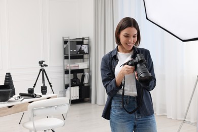 Photo of Young professional photographer with camera in photo studio, space for text