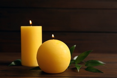 Wax yellow candles of different shapes on wooden table