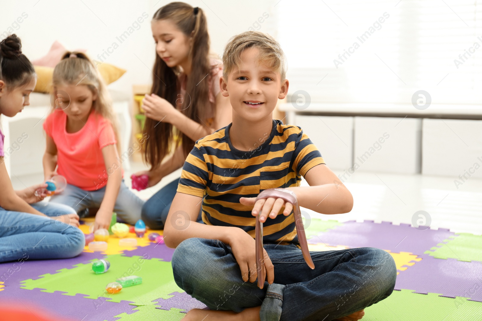 Photo of Preteen boy playing with slime in room