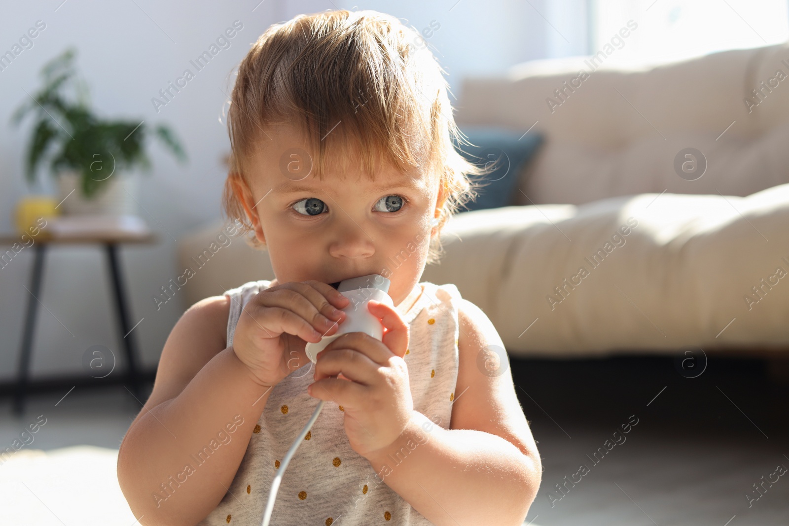 Photo of Cute baby with charger at home. Dangerous situation